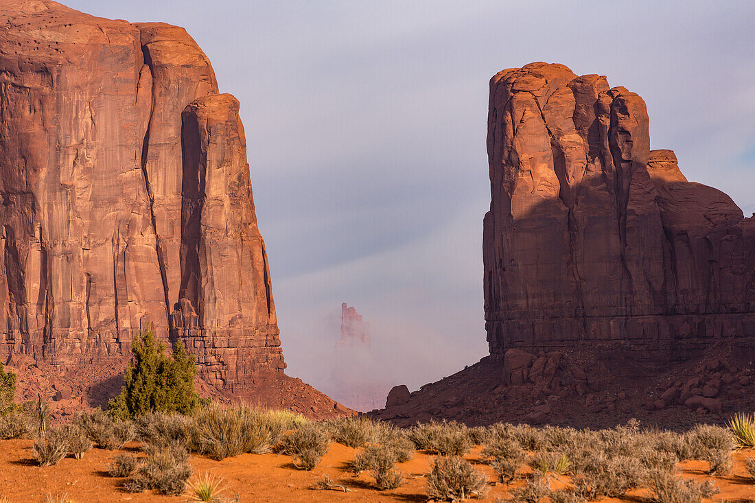 Foggy morning North Window view of the the BIg Indian Chief framed by Elephant Butte & Cly Butte in the Monument Valley Navajo Tribal Park in Arizona. L-R: Elephant Butte, Big Indian Chief & Cly Butte.