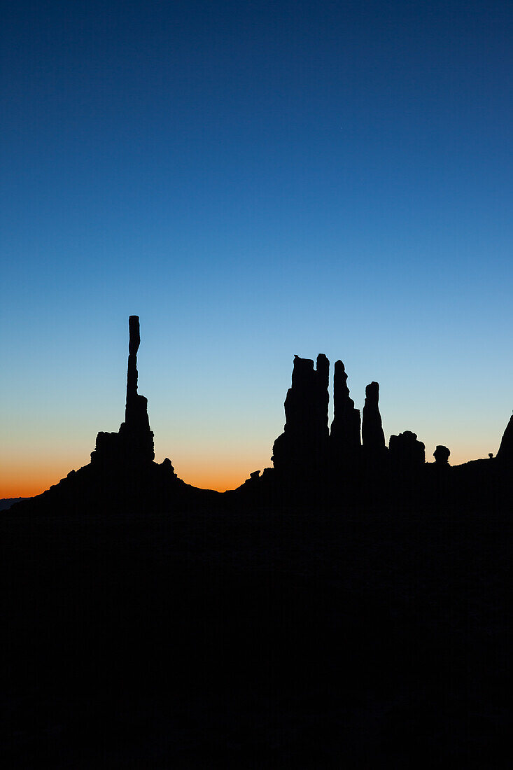 Der Totempfahl und der Yei Bi Chei in der Silhouette vor Sonnenaufgang im Monument Valley Navajo Tribal Park in Arizona