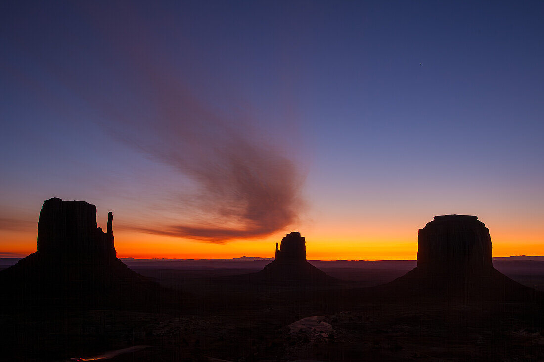 Curved cloud over the Mittens & Merrick Butte before sunrise in the Monument Valley Navajo Tribal Park in Arizona.