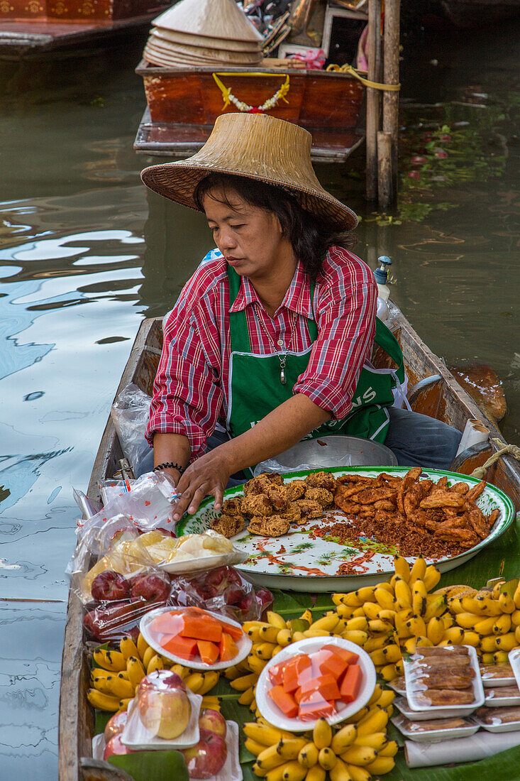 A Thai woman preparing food on her boat in the Damnoen Saduak Floating Market in Thailand.
