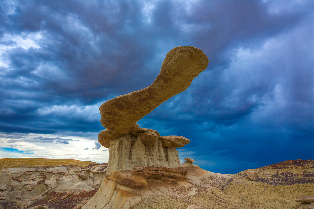 The King of Wings, a very fragile sandstone hoodoo in the badlands of the San Juan Basin in New Mexico, with storm clouds behind.