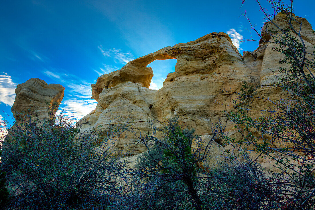 Blauer Himmel und Wolken über dem Graceful Arch in einer abgelegenen Wüste bei Aztec im Nordwesten von New Mexico