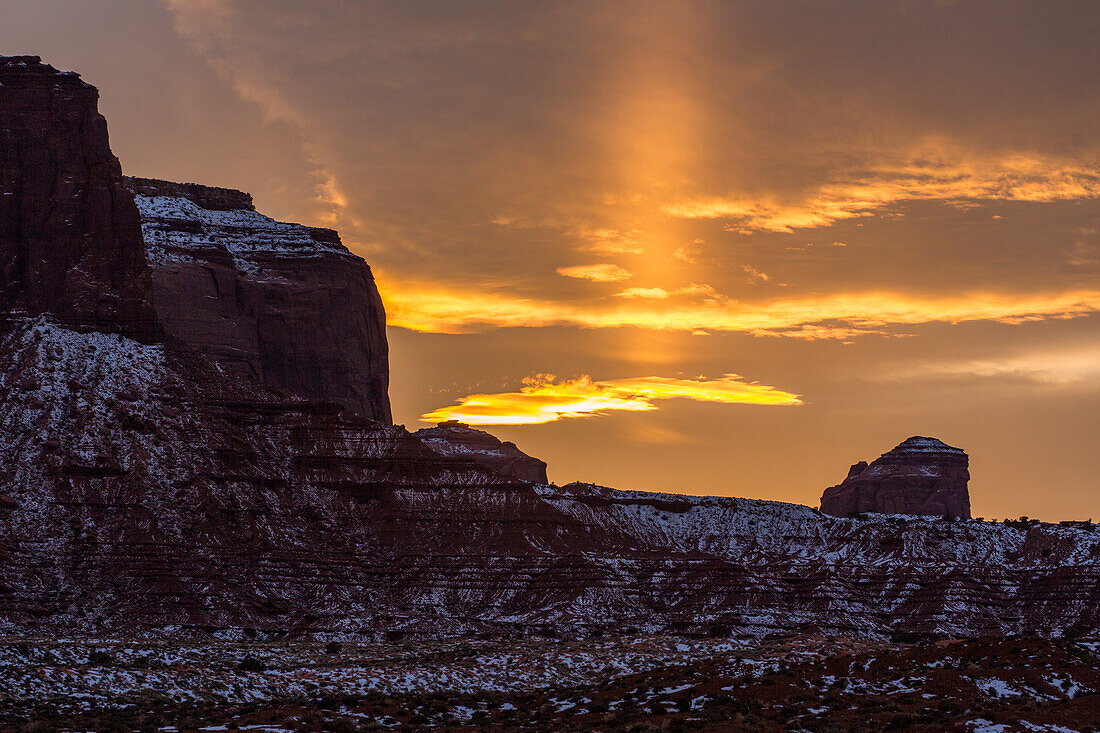 Eine Sonnensäule bei Sonnenuntergang im Monument Valley Navajo Tribal Park in Arizona. Sonnensäulen sind Sonnenlicht, das von atmosphärischen Eiskristallen reflektiert wird.