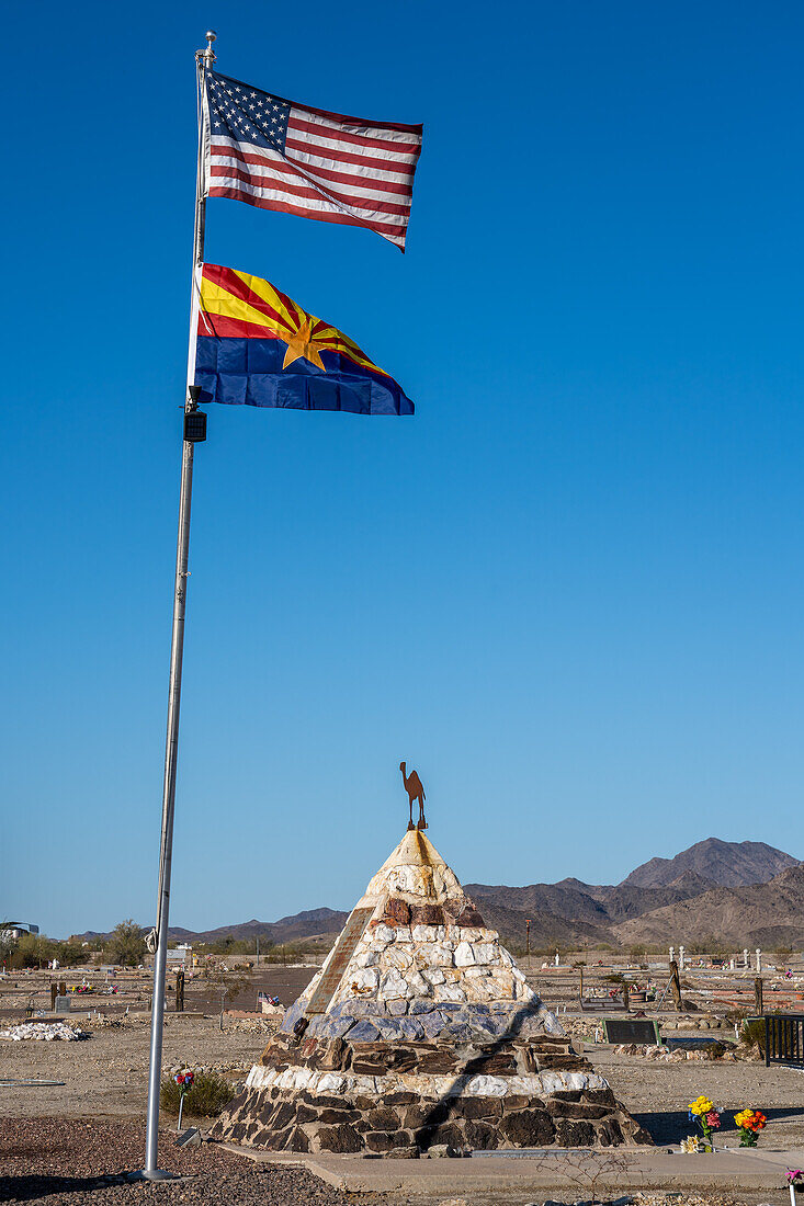 Flaggen über dem Grabdenkmal von Hadji Ali, oder Hi Jolly, auf dem Friedhof in Quartzsite, Arizona, mit den Dome Rock Mountains im Hintergrund