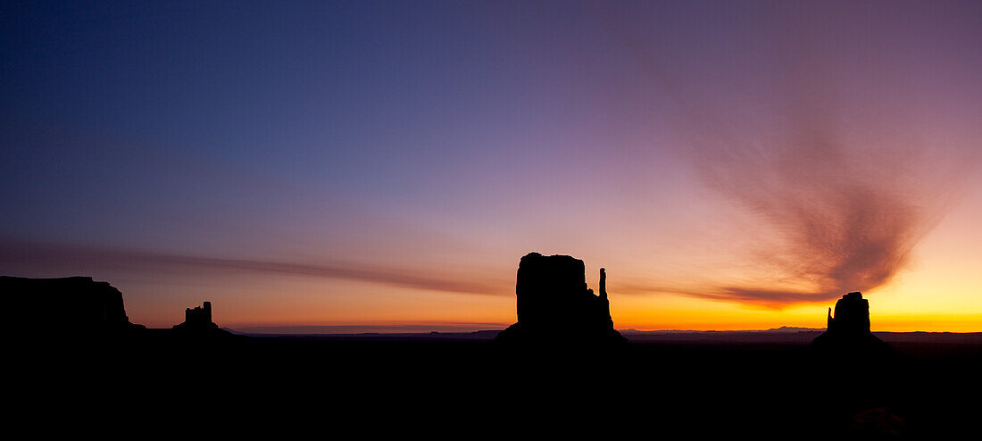 Curved cloud over the Mittens before sunrise in the Monument Valley Navajo Tribal Park in Arizona.