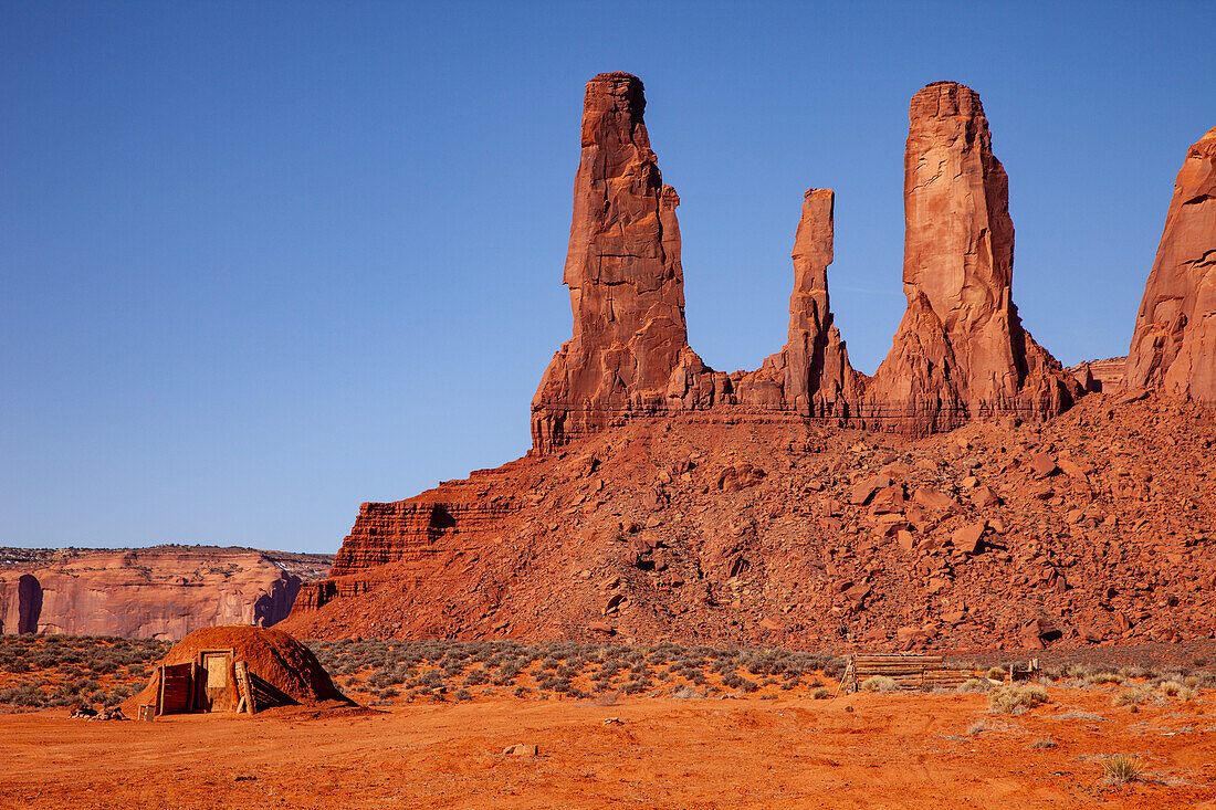 A traditional Navajo hogan in front of the Three Sisters in the Monument Valley Navajo Tribal Park in Arizona.