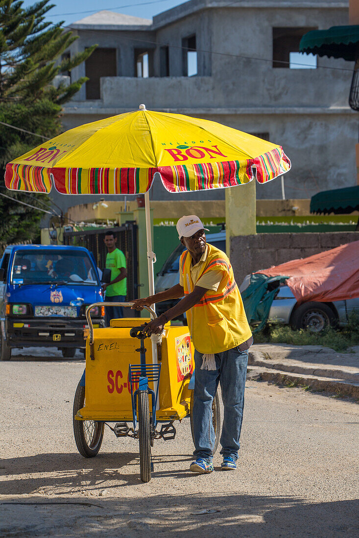 Ein haitianischer Einwanderer, der in der Dominikanischen Republik von einem fahrbaren Wagen aus Eiscreme auf der Straße verkauft