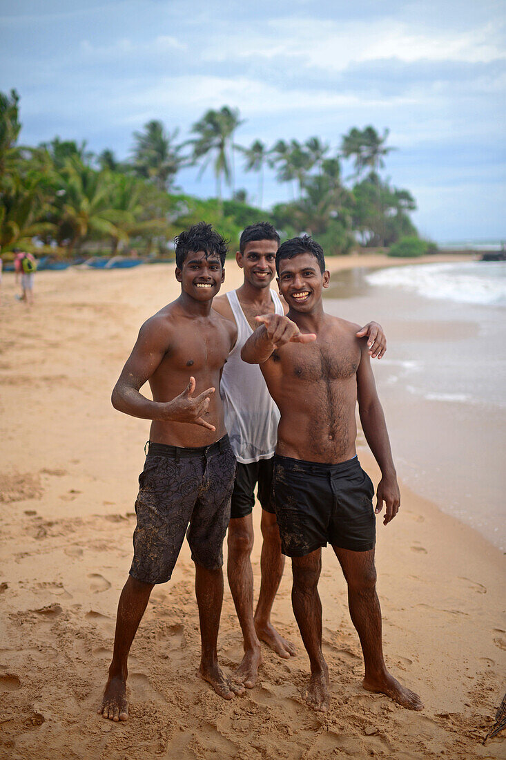 Drei junge Männer am Strand von Hikkaduwa, Sri Lanka