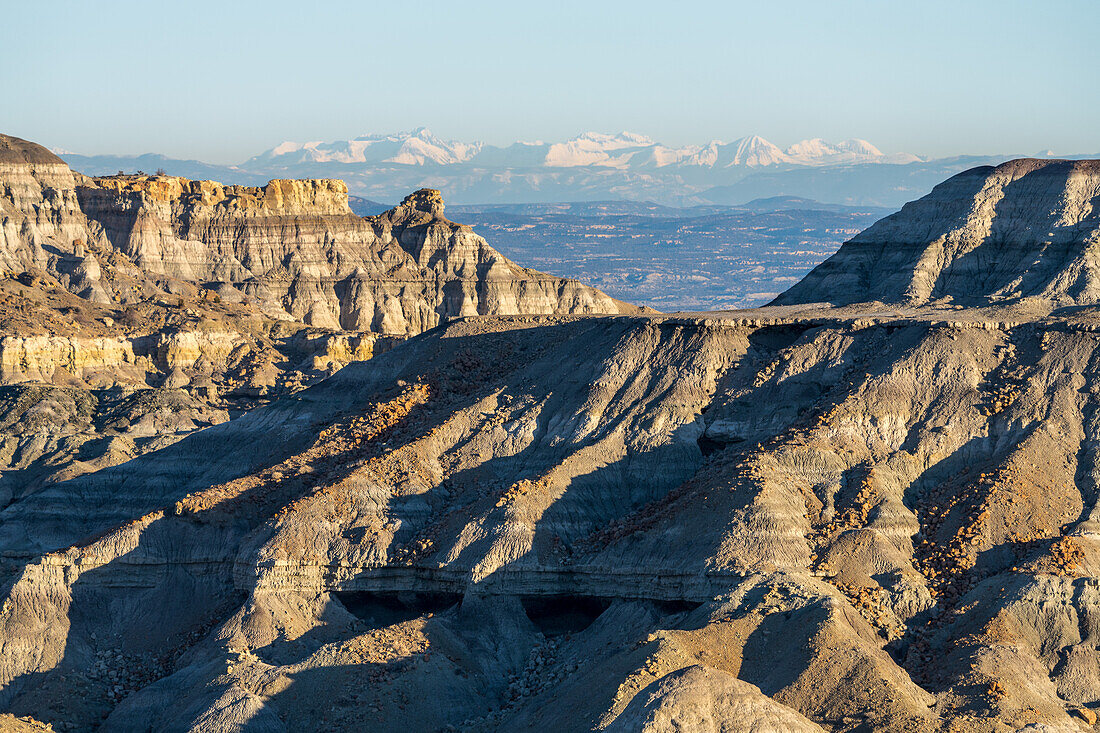 Angel Peak Scenic Area near Bloomfield, New Mexico. The Kutz Canyon badlands with the snow-capped San Juan Mountains behind.