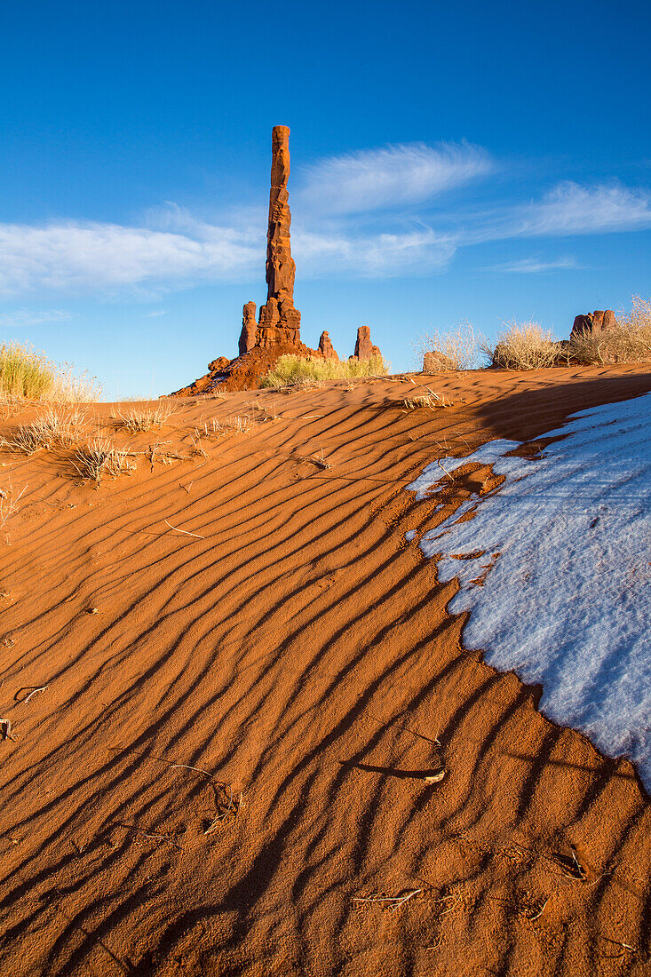 The Totem Pole with snow and rippled sand in the Monument Valley Navajo Tribal Park in Arizona.