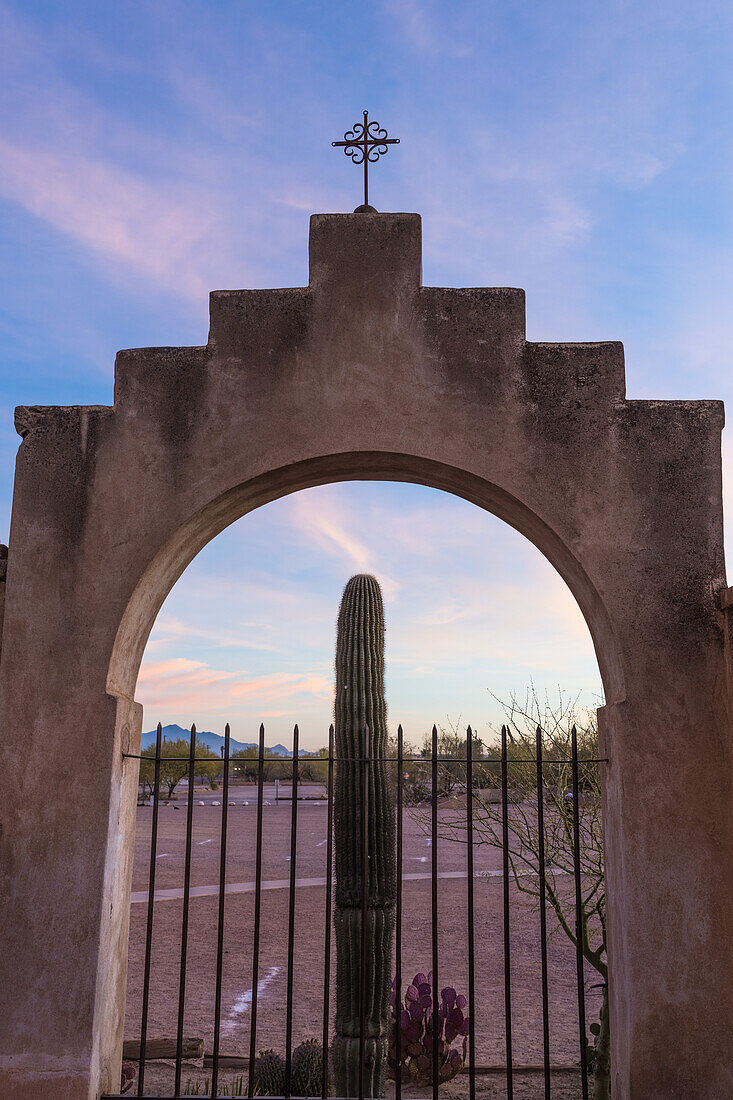 Ein Saguaro-Kaktus vor dem gewölbten Eingangstor der Mission San Xavier del Bac in Tucson, Arizona