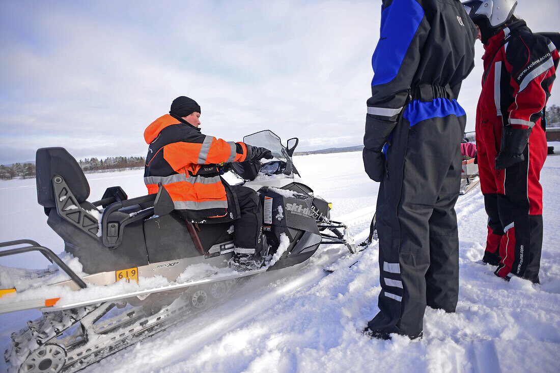 Antti, young Finnish guide from VisitInari, explains how to ride a snowmobile in the wilderness of Inari, Lapland, Finland