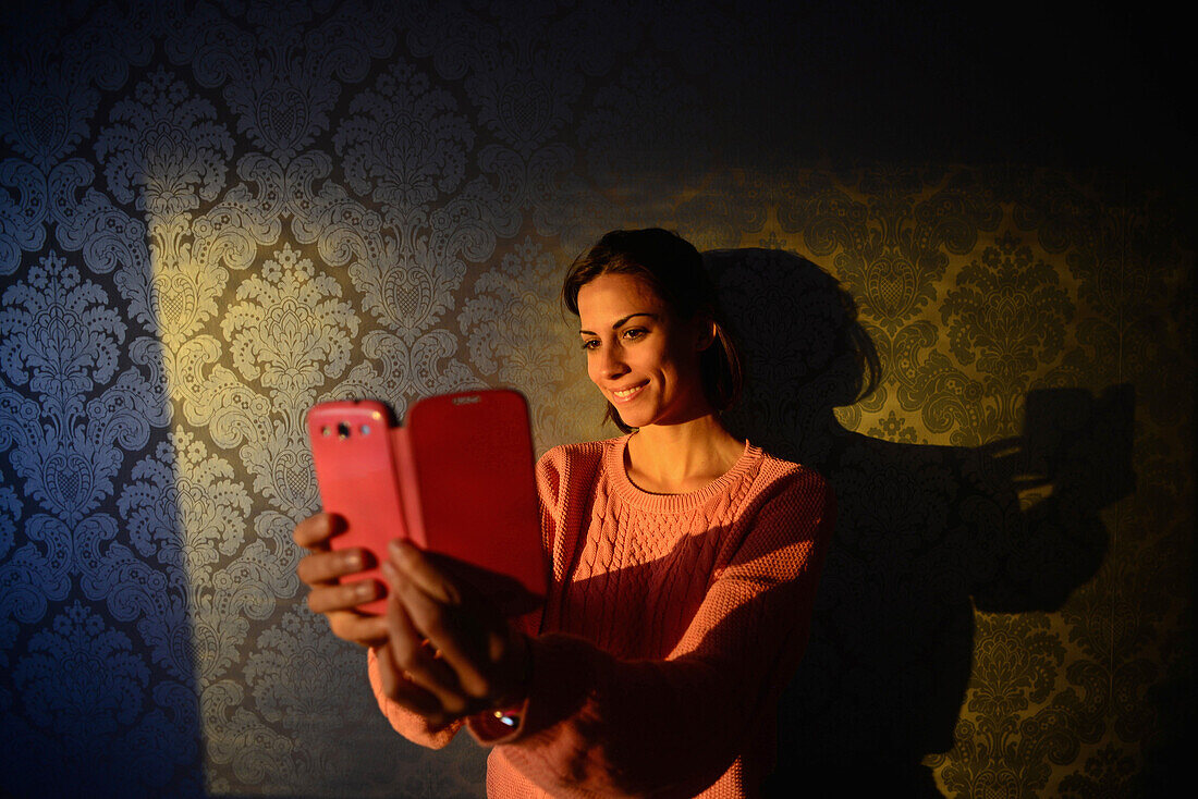 Junge Frau macht ein Selfie mit Handy im Hotelzimmer, Kemi, Lappland