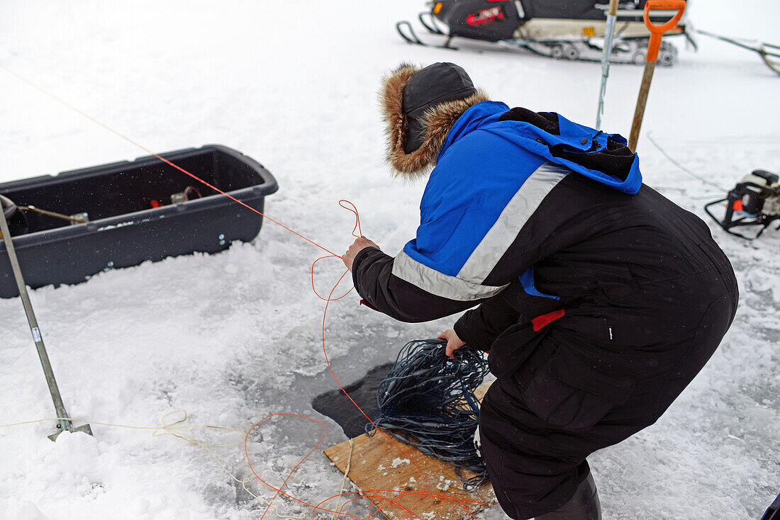 Fischer beim Eisfischen im Inari-See, Lappland, Finnland