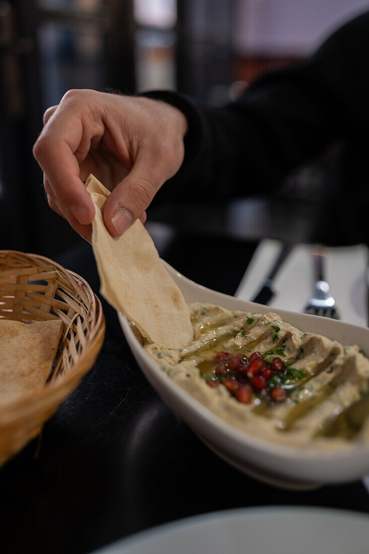 Männerhand beim Verzehr eines Hummus-Gerichts im Restaurant Mosaico, Zaragoza, Spanien