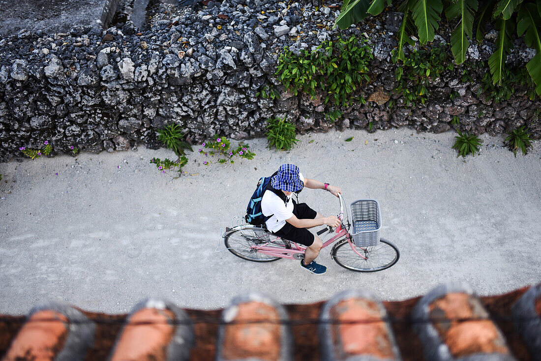 Mann fährt Fahrrad auf der Insel Taketomi, Präfektur Okinawa, Japan