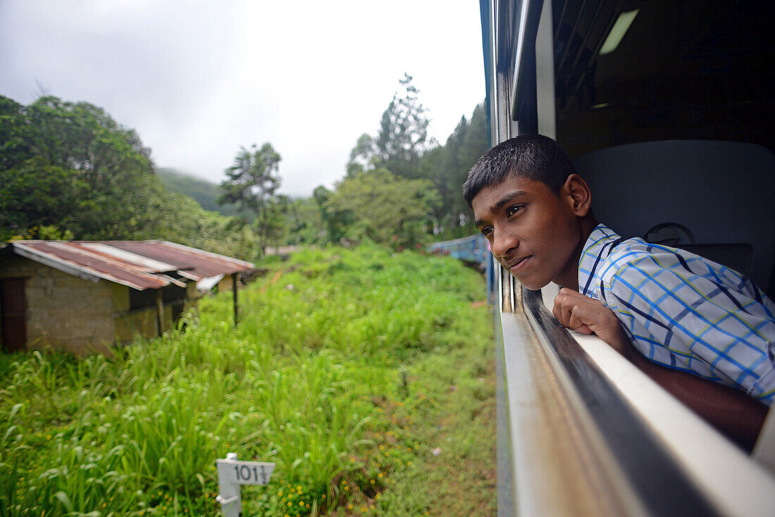 Porträt eines kleinen Jungen am Fenster. Zugfahrt von Kandy nach Nuwara Eliya, Sri Lanka
