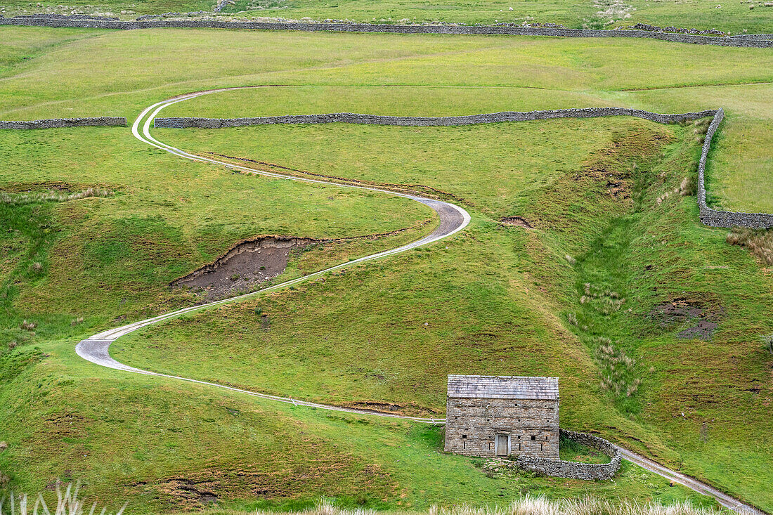 zigzag road in a field in Yorkshire Dales England with a stone house