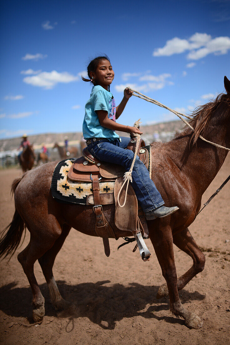 Cute young native american girl riding her horse during Navajo Nation Fair, a world-renowned event that showcases Navajo Agriculture, Fine Arts and Crafts, with the promotion and preservation of the Navajo heritage by providing cultural entertainment. Window Rock, Arizona.