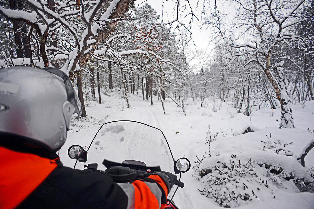 Antti, young Finnish guide from VisitInari, rides a snowmobile in the wilderness of Inari, Lapland, Finland