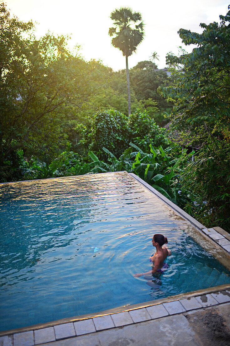 Young attractive woman enters an infinity edge swimming pool at The Dutch House, Galle, Sri Lanka