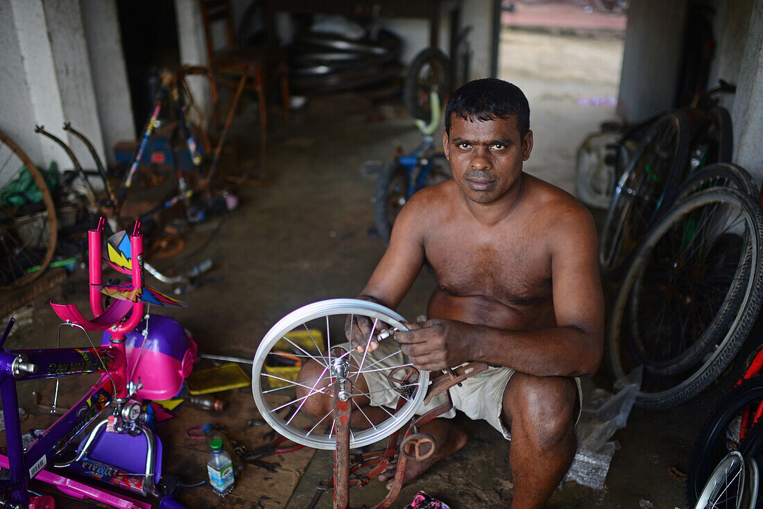 Mann repariert ein Fahrrad in einer Fahrradwerkstatt, Ahangama, Sri Lanka