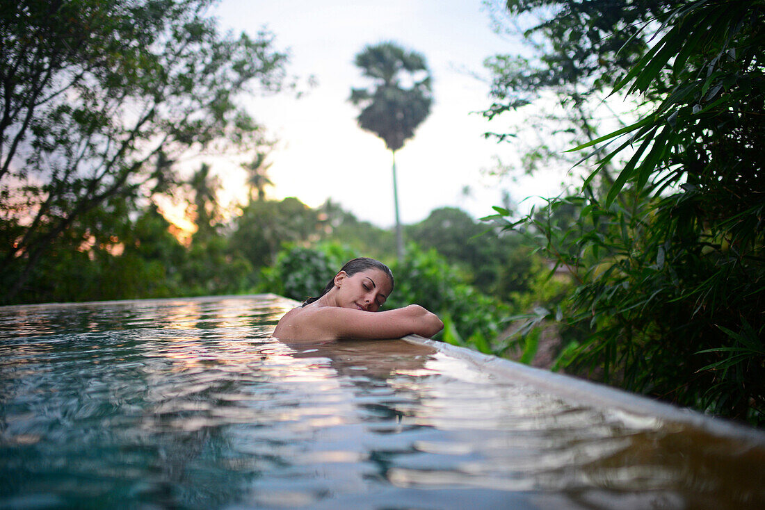 Young attractive woman enjoying a bath in the infinity edge swimming pool at The Dutch House, Galle, Sri Lanka