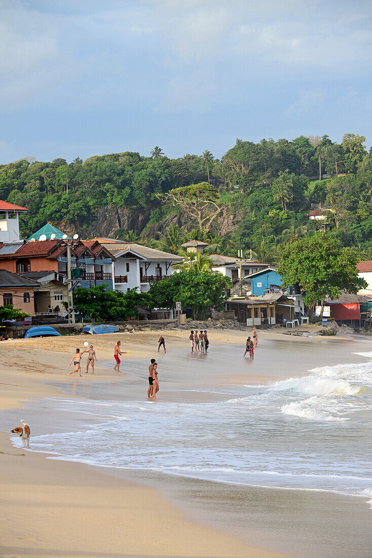 Einheimische und Touristen genießen einen sonnigen Tag am Strand von Unawatuna im Bezirk Galle, Sri Lanka