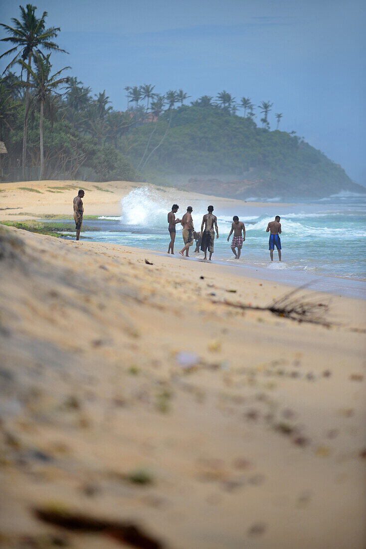 Eine Gruppe junger Männer amüsiert sich am Strand von Midigama, Sri Lanka