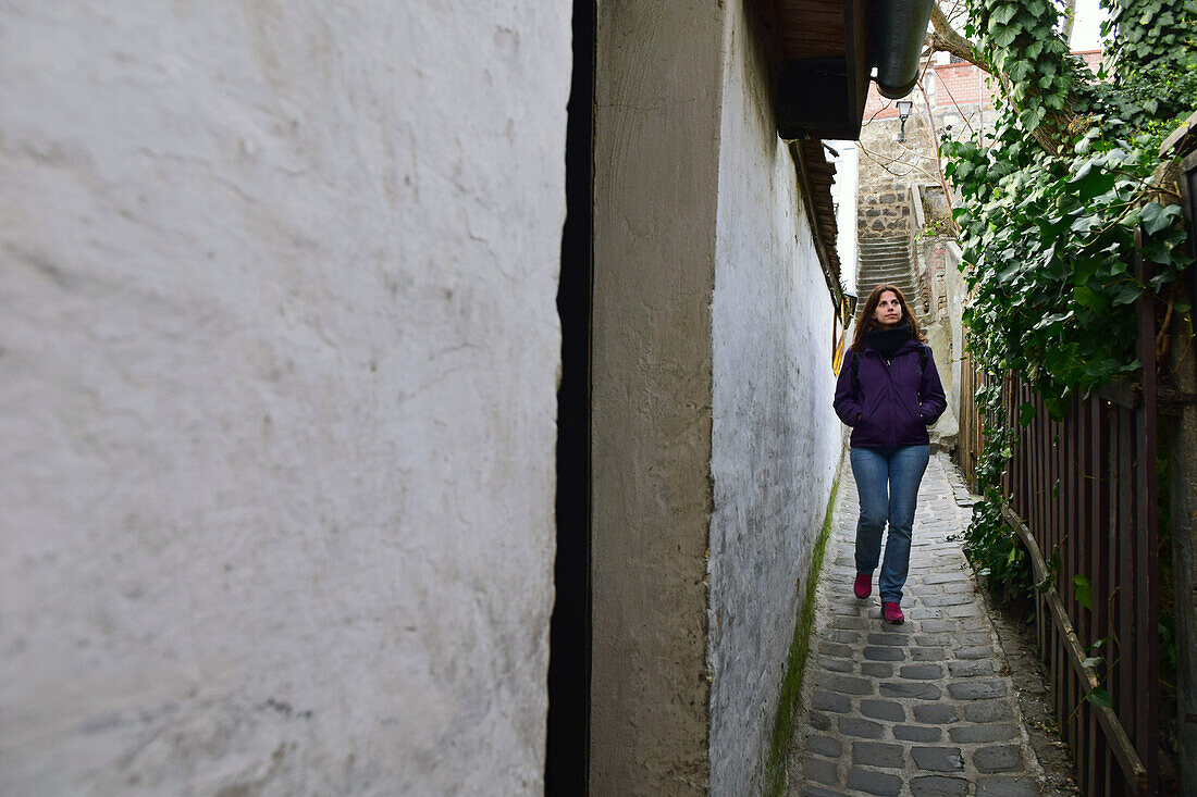 Junge Frau geht in einer engen Straße in Szentendre, Ungarn, spazieren