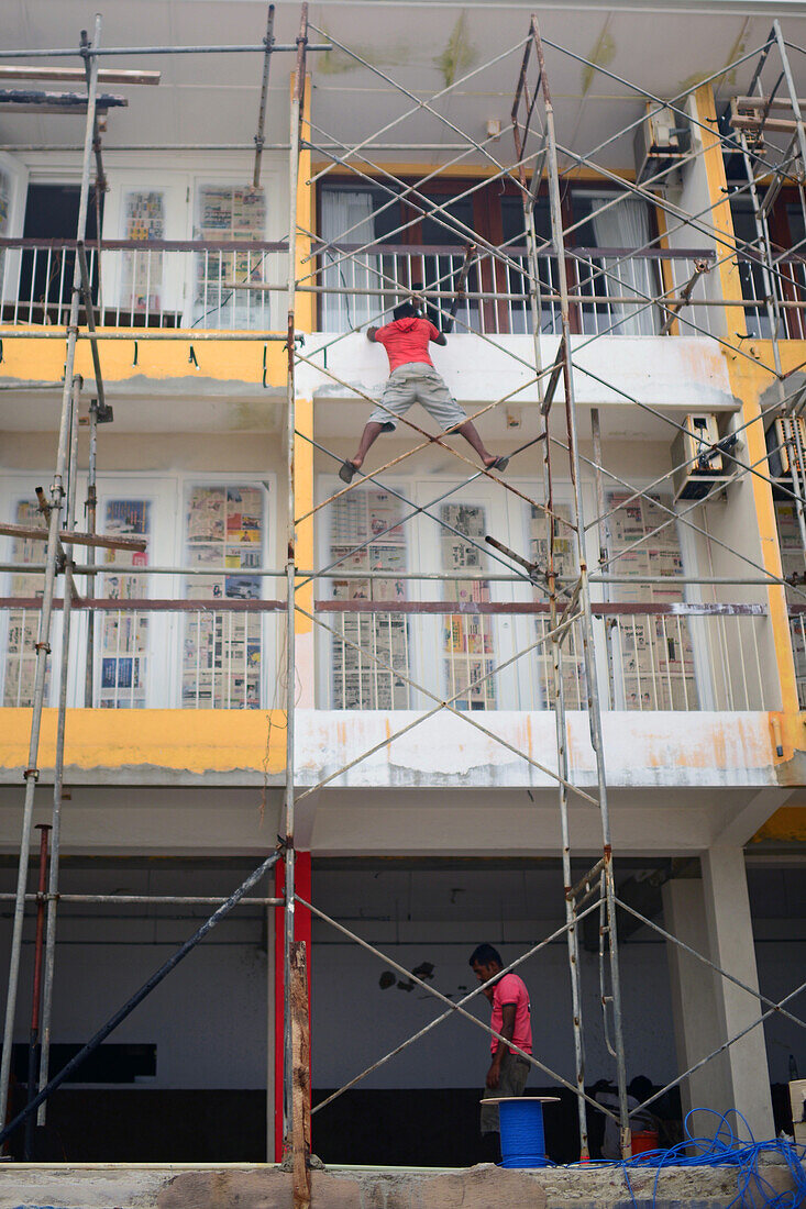 Bauarbeiter veranschaulicht das Konzept des Berufsrisikos bei der Arbeit auf einem hohen Gerüst, Sri Lanka
