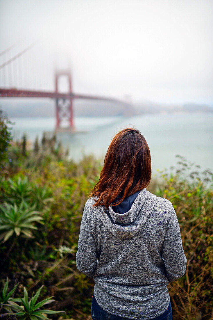 Young woman looking at Golden Gate Bridge, San Francisco.