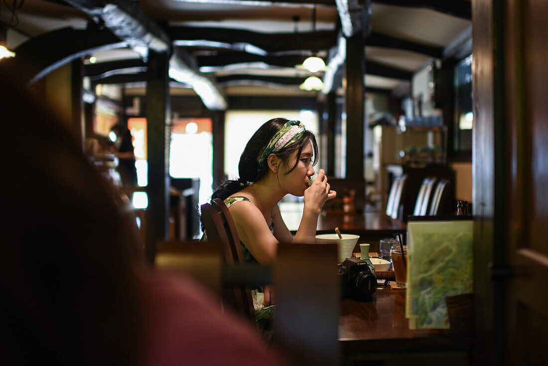 Junge Frau beim Essen in einem Restaurant, Shirakawa-go, traditionelles Dorf mit einem als gassho-zukuri bekannten Baustil, Präfektur Gifu, Japan