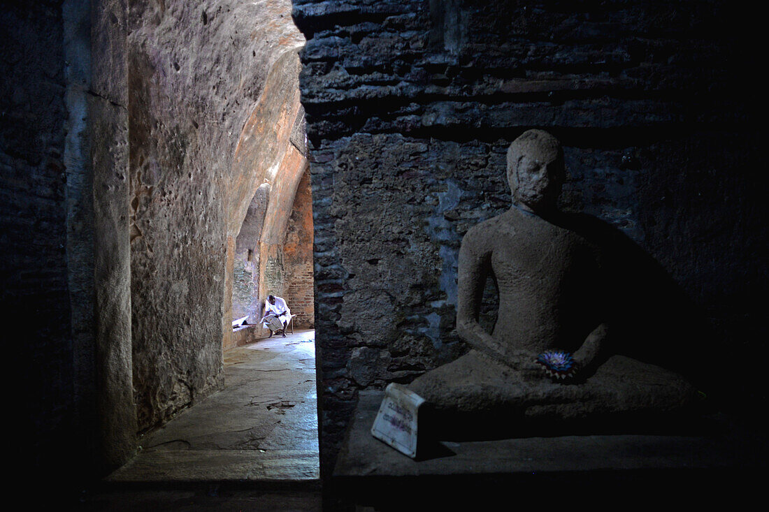 Lesender Mann und Buddha-Statue in Thuparama in der antiken Stadt Polonnaruwa, Sri Lanka