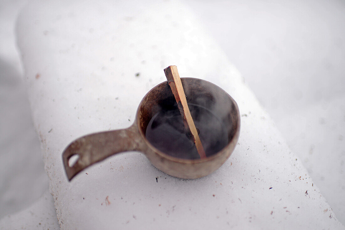 Hölzerne Tasse mit heißem Saft. Inari-See, Lappland, Finnland
