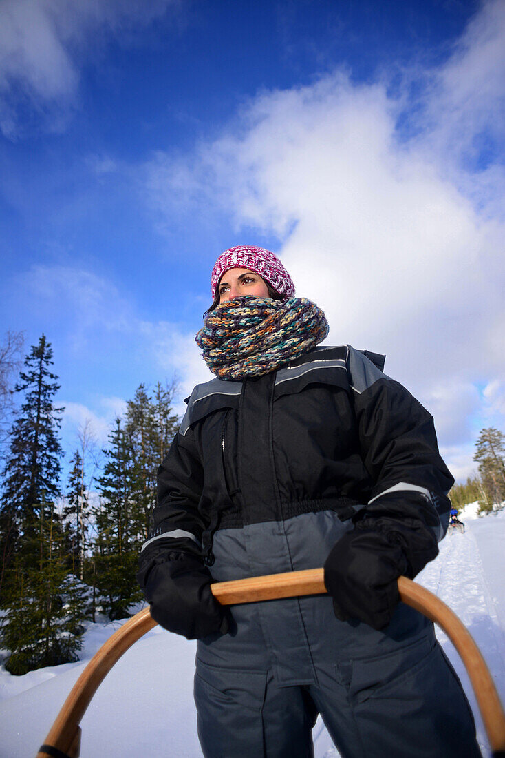 Junge Frau am Steuer eines Schlittens. Wildnis-Husky-Schlittentour in der Taiga mit Bearhillhusky in Rovaniemi, Lappland, Finnland