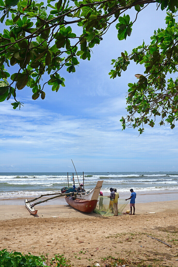Fischer und traditionelle Fischerboote in Weligama, Sri Lanka