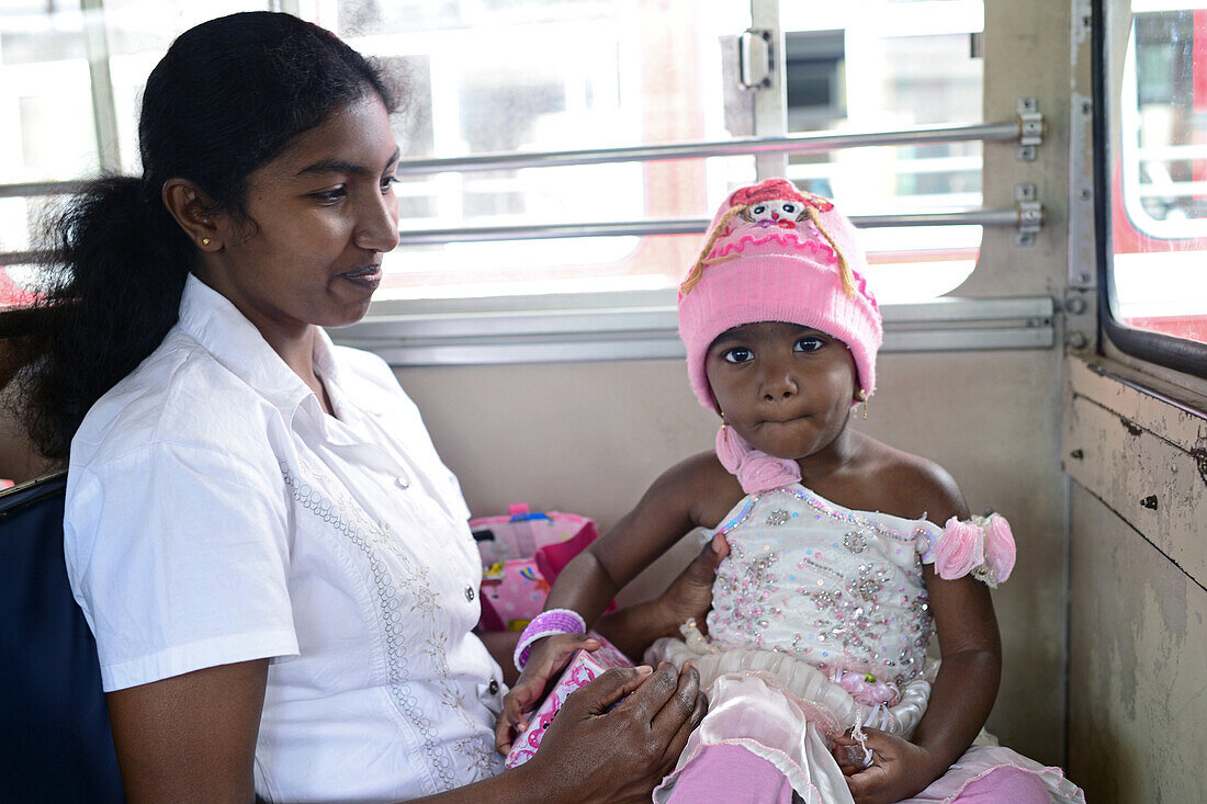 Young woman holding baby in bus, Sri Lanka