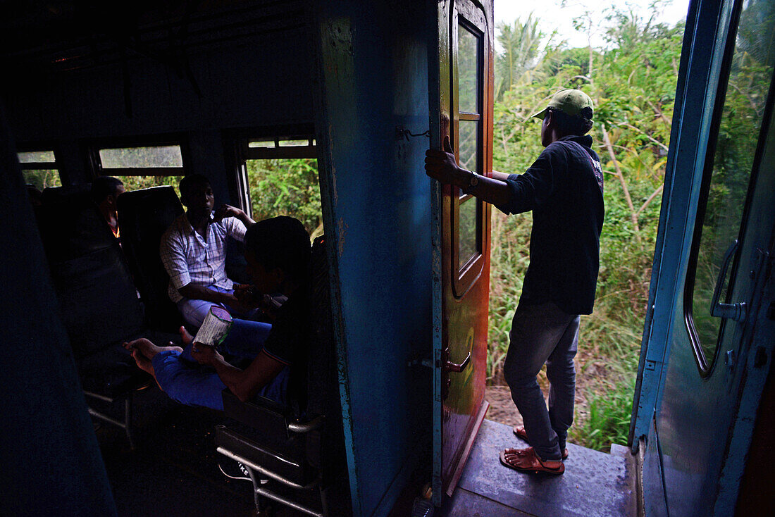 Young man looking through train open door, Sri Lanka