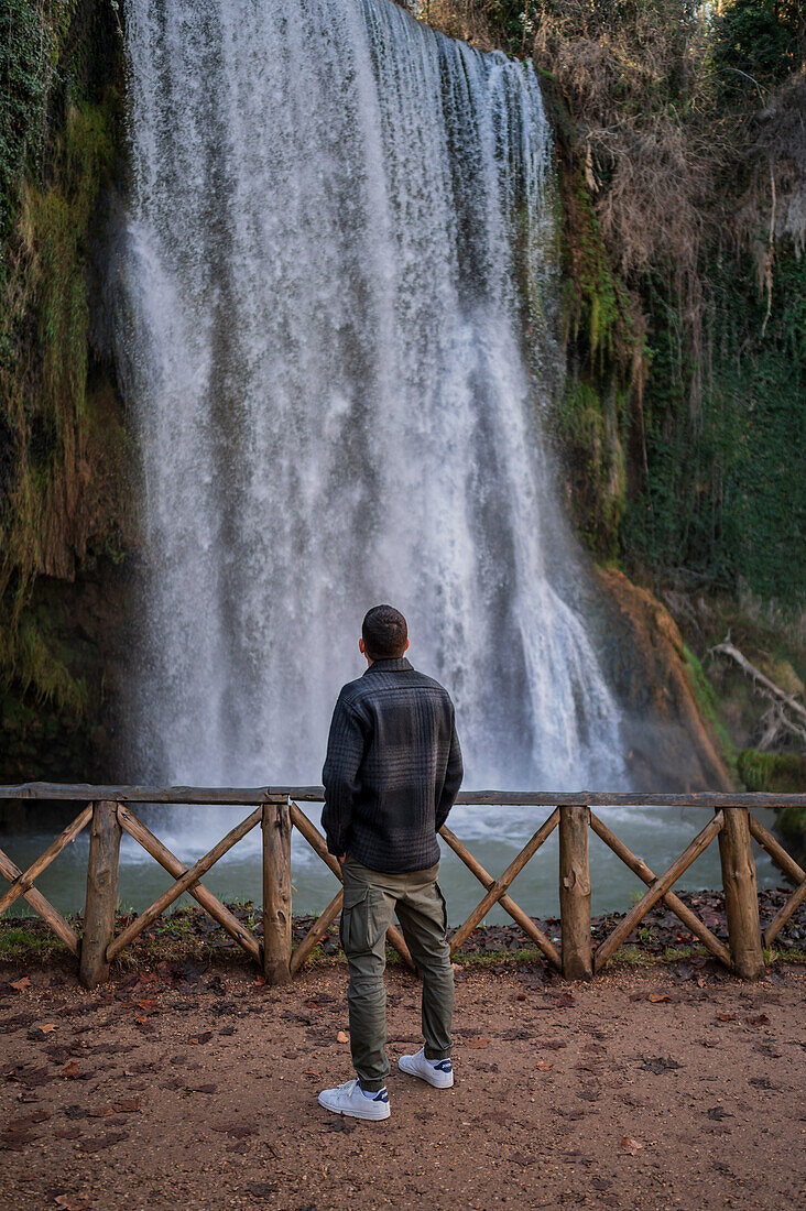 Young man looking at a waterfall in Monasterio de Piedra Natural Park, located around the Monasterio de Piedra (Stone Monastery) in Nuevalos, Zaragoza, Spain