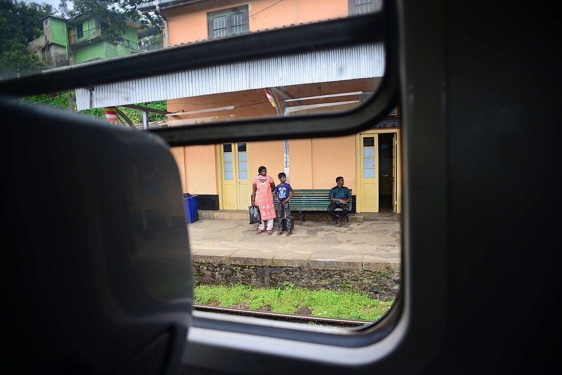 Familie wartet auf den Zug, Blick aus dem Fenster auf den Bahnsteig. Zugfahrt von Kandy nach Nuwara Eliya, Sri Lanka
