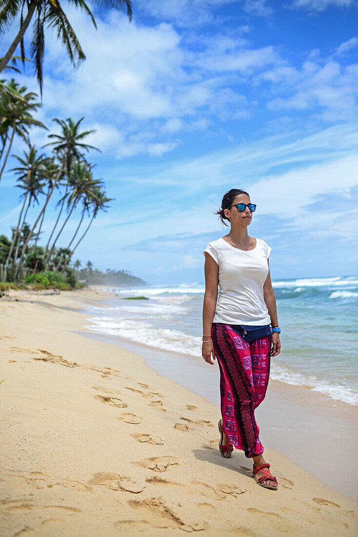 Junge Frau beim Spaziergang am Strand zwischen Weligama und Ahangama, Sri Lanka