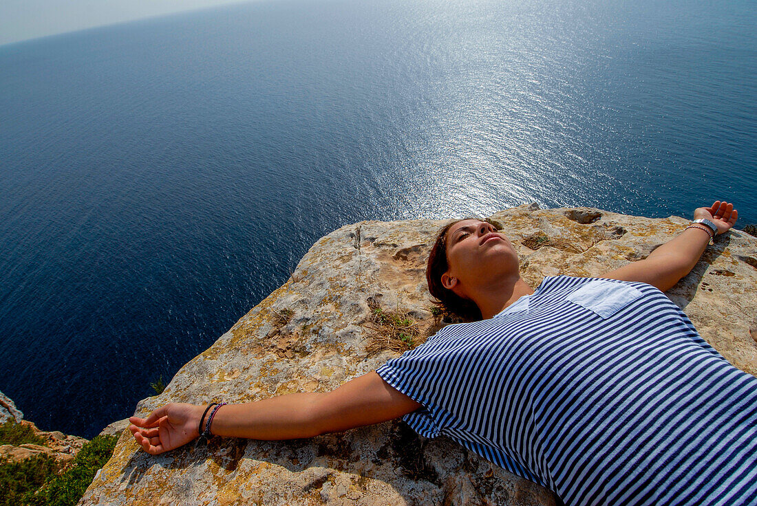 Young woman relaxing on a coastal rock, Formentera