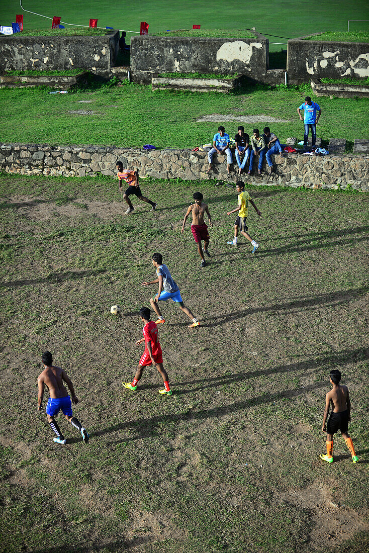 Straßenfußballspiel auf einem improvisierten Feld neben dem UNESCO-Weltkulturerbe Galle Fort, während des Binara-Vollmond-Poya-Tages