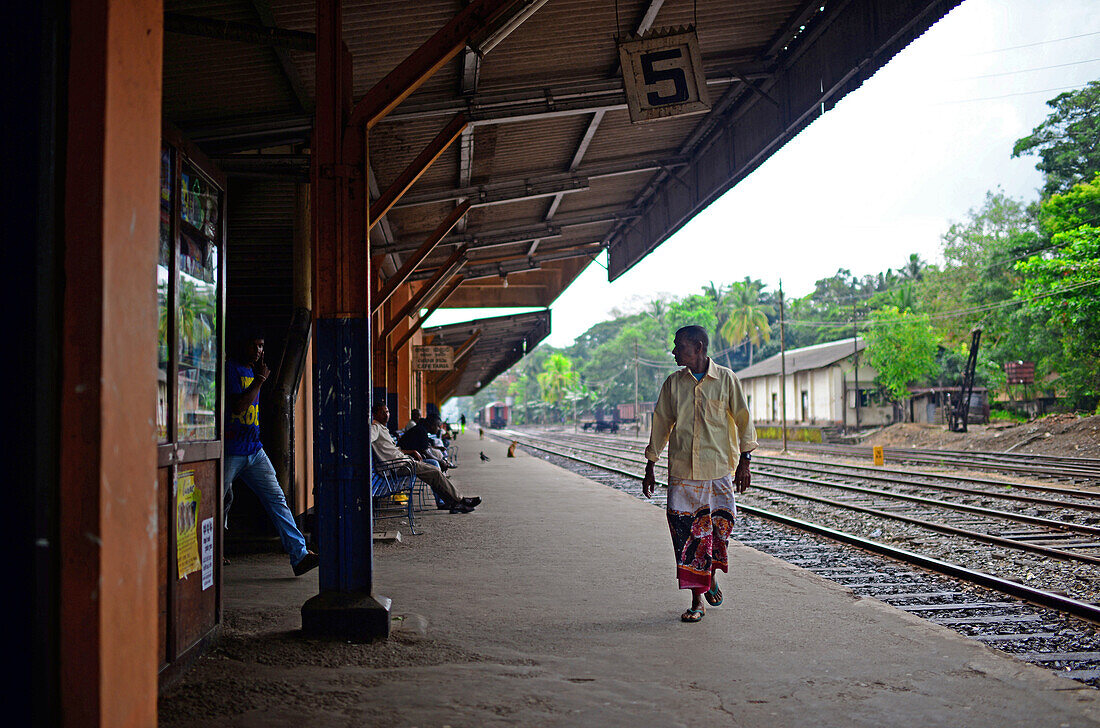 Mann geht auf dem Bahnsteig eines Bahnhofs, Sri Lanka