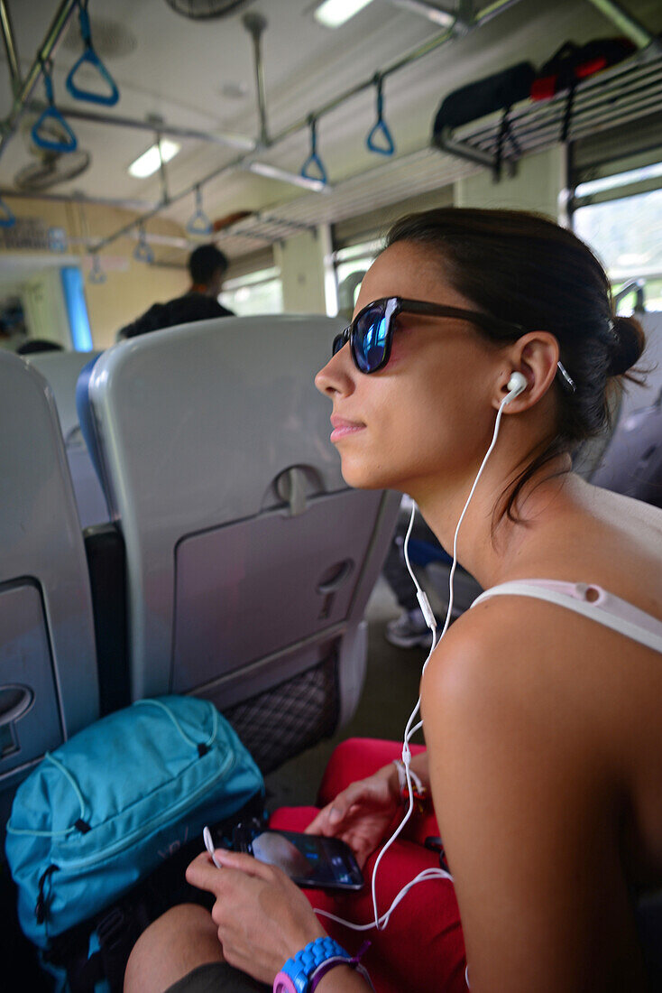 Junge Frau hört Musik in einem Bus, Sri Lanka