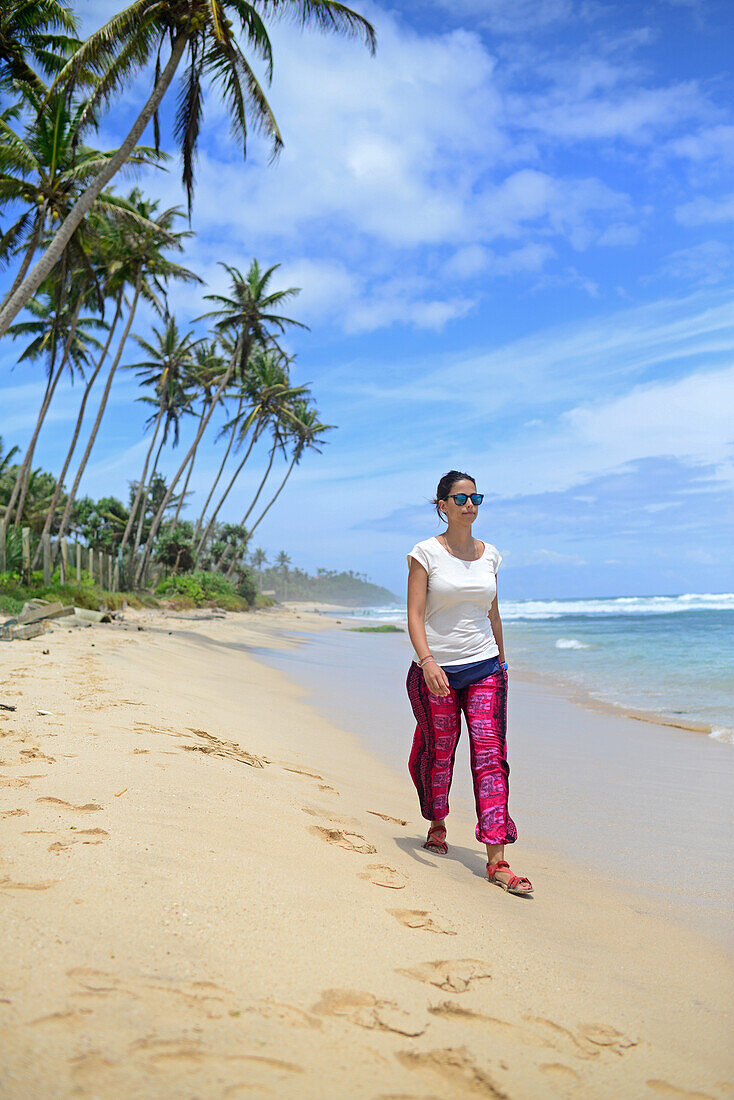 Junge Frau beim Spaziergang am Strand zwischen Weligama und Ahangama, Sri Lanka