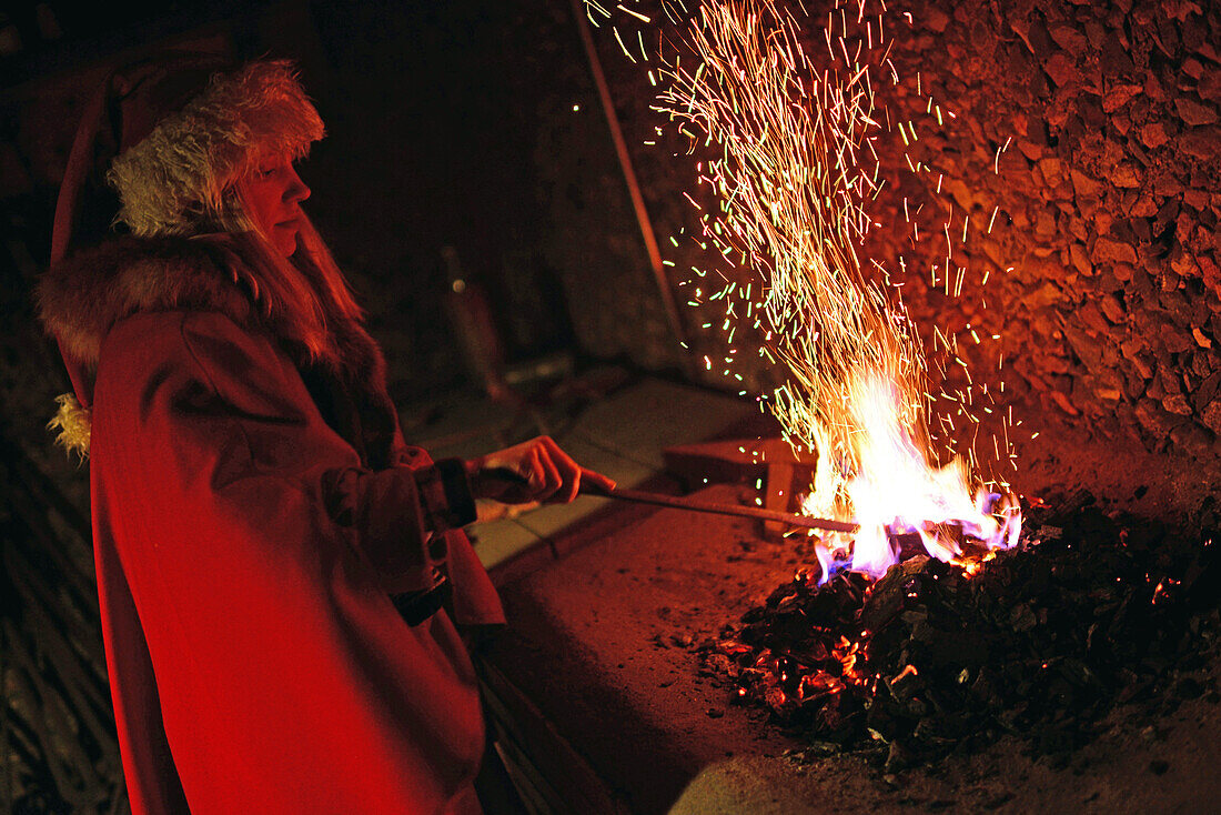 Junge Elfe wirft magisches Pulver ins Feuer. Kakslauttanen Arctic Resort in Saariselka, Finnland