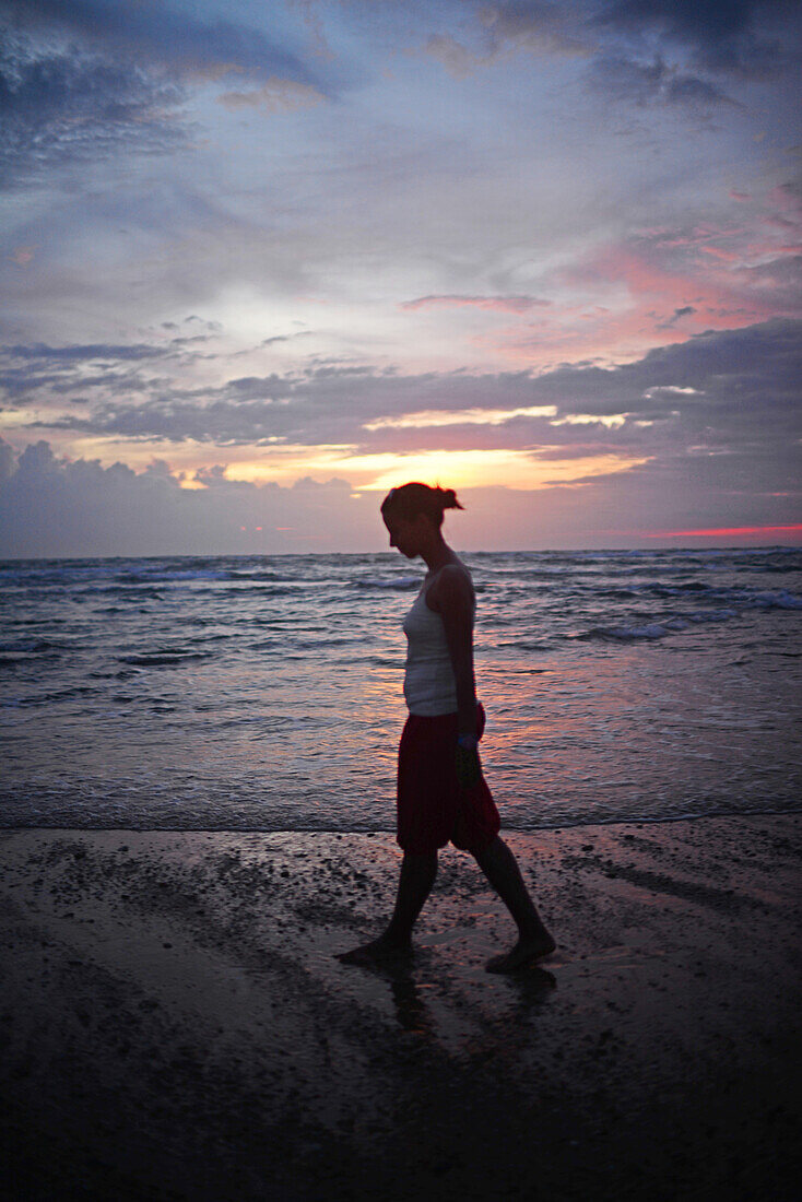 Junge Frau genießt den Sonnenuntergang am Strand von Hikkaduwa, Sri Lanka