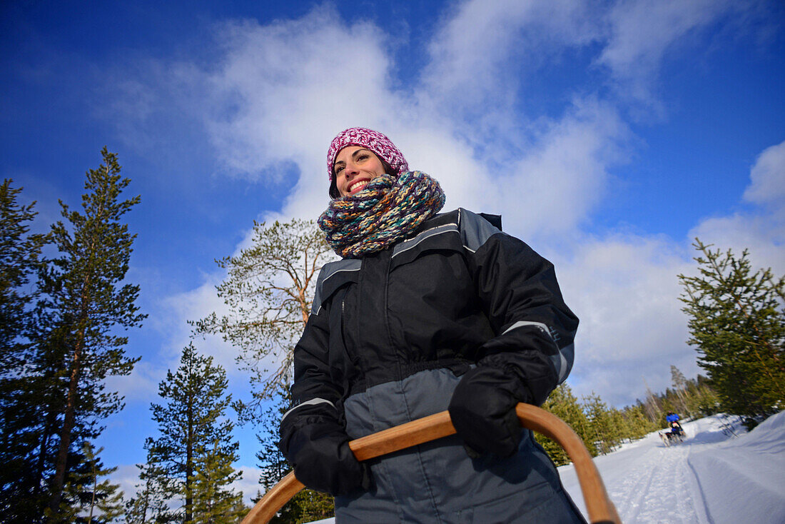 Junge Frau am Steuer eines Schlittens. Wildnis-Husky-Schlittentour in der Taiga mit Bearhillhusky in Rovaniemi, Lappland, Finnland
